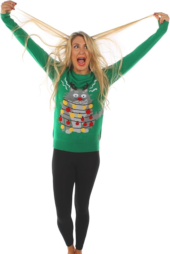 Barefoot party queen yanks her blonde hair and beams in a wild green sweater flaunting a hilariously zapped Christmas cat.