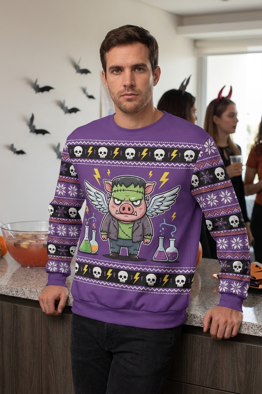 A man leans on a kitchen counter at a Halloween house party with paper bats on the wall behind him, wearing the Frankenswine all-over-print sweatshirt